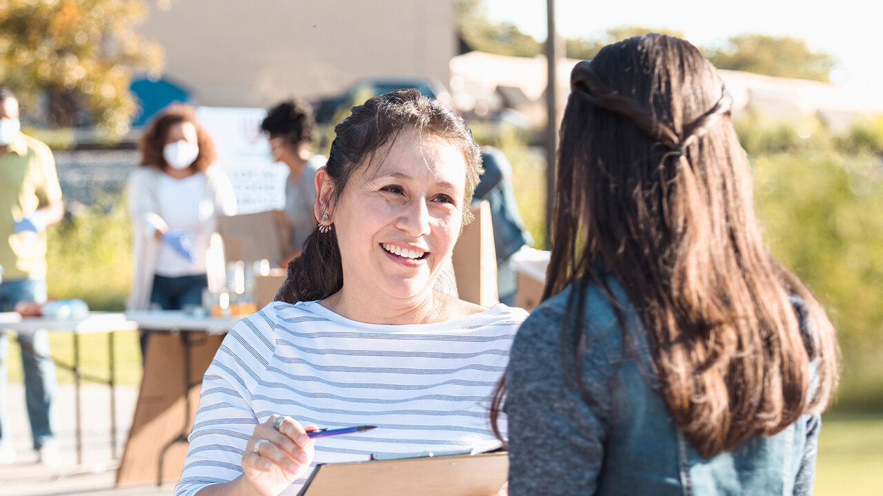 Campaign volunteer meeting with voter at community event.